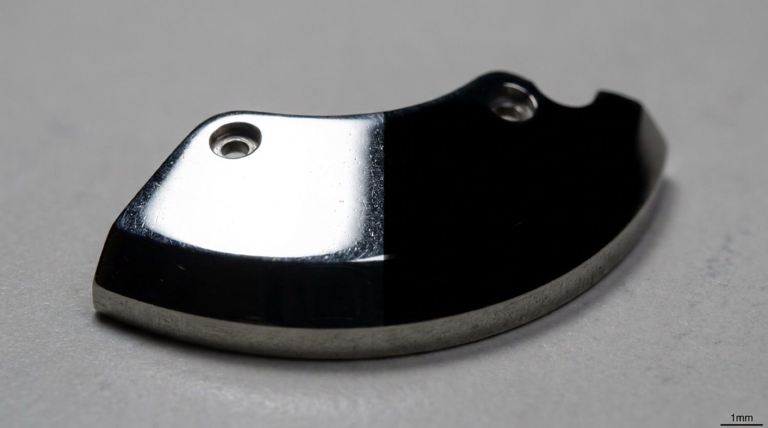 Macro of a black-polished (poli noir) steel component, mirror-bright from one angle and pitch black from another